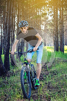 Man in a helmet riding on a mountain bike in the woods among the