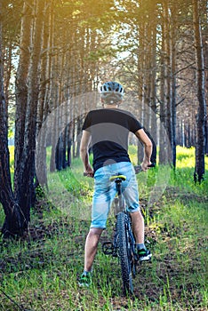 Man in a helmet riding on a mountain bike in the woods among the