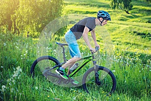 Man in a helmet riding on a mountain bike in the woods. Cyclist