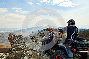 Man in helmet sitting on ATV quad bike in mountains