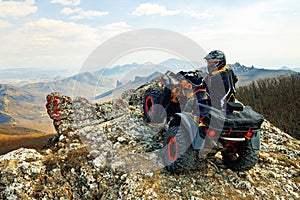 Man in helmet sitting on ATV quad bike in mountains