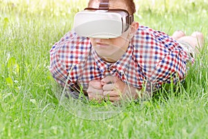 Man in a helmet of virtual reality lies on a green grass