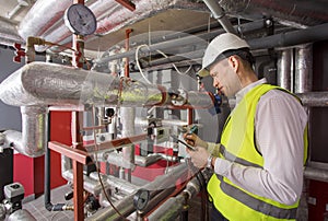 Man in helmet writing down measurements in heat photo