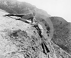 Man helping another man from falling down a cliff photo