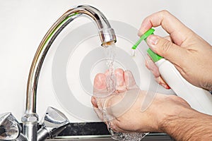 Man helping himself to dollop of antibacterial soap, close up of hands. Washing hands rubbing with soap man for winter flu virus