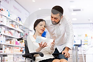 Man helping his disabled wife to choose pharmaceuticals in drugstore