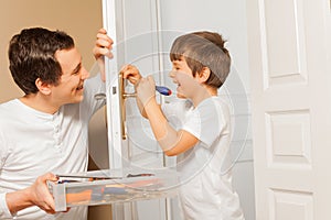 Man helping his son to draw up bolt of door handle