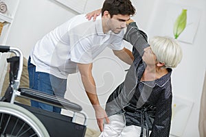 Man helping lady into wheelchair