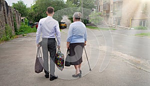 Man helping old woman to carry bags