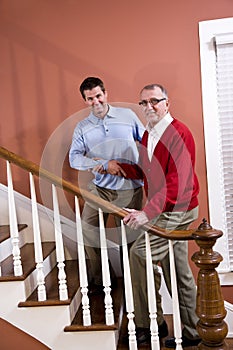 Man helping senior father climb stairs at home