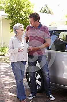 Man Helping Senior Woman Into Car