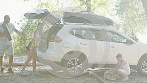 Man helping woman preparing for picnic, boy and dog near car