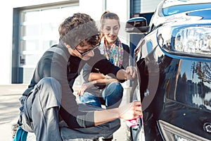 Man helping woman cleaning rims in car wash photo