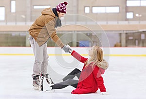 Man helping women to rise up on skating rink