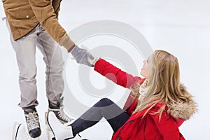 Man helping women to rise up on skating rink