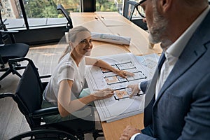 Man helps a colleague, a woman in wheelchair, with work