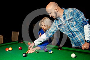 Man helps a girl to play pool on the billiard table