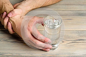 The man helps himself with his second hand to take a glass of water. Essential tremor and Parkinson`s disease