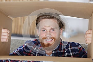 man hides face inside cardboard box