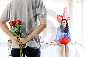 Man hiding beautiful red rose bouquet behind back, ready to give Valentine flower present to lover girlfriend for celebration,