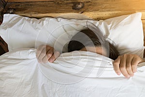 Man hiding in bed under the blanket at home.