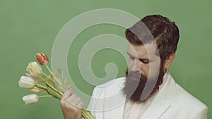 Man hiding behind a bouquet of flowers. Proposal scene. Portrait of thinking stylish young man looking away. Handsome