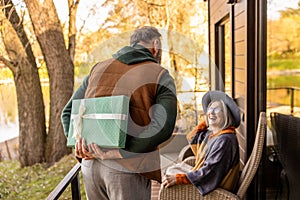 Man hiding a gift and a woman looking anticipated and excited