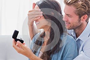 Man hiding his wifes eyes to offer her an engagement ring