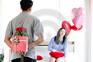 Man hiding red gift box with beautiful red rose bouquet behind back, ready to give Valentine present to lover girlfriend for