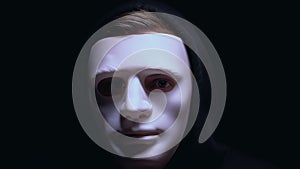Man hiding wounded face under mask, isolated on black background, criminal