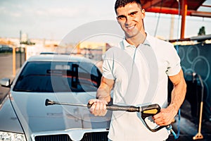 Man with high pressure washer on car wash station