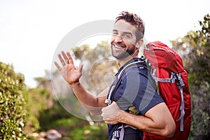 Man, hike and happy with wave for adventure with backpack for fitness, workout and hobby in Canada. Portrait, smile and