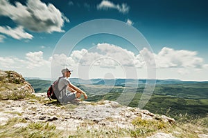 Man hiker with backpack relaxing on top of a mountain