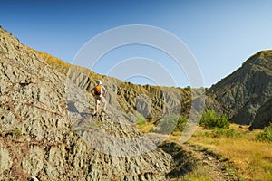 Man hiker with backpack standing in a badland canyon