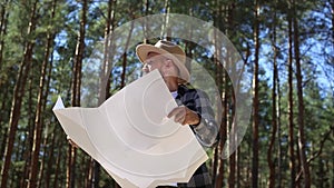 Man hiker consults a map in the forest. Composition hiking.