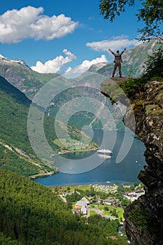 Man hiker enjoying scenic landscapes at a cliff edge, Geirangerfjord