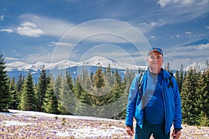 Man hiker enjoys saffron blooming at Carpathian mountains