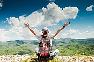 Man hiker greeting rich nature on the top of mountain