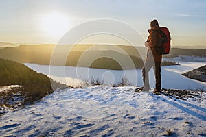 Man hiker hiking in winter. Traveler hiking in winter and enjoying mountains landscape at sunset.