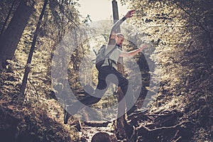 Man hiker jumping across stream