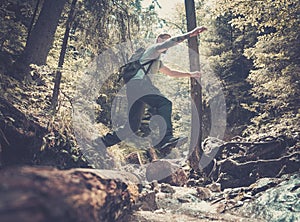 Man hiker jumping across stream