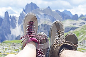 Man hiker lie on a ground. Peaks like a background. Sunny day.Trekking boots.Lens flare. Succesful backpacker enjoy a view.