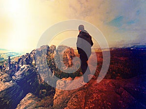 Man hiker at mountain peak. Marvelous daybreak in autumn misty landscape. Abstract effect.