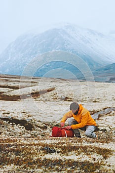 Man hiker packing backpack in mountains travel adventure vacations