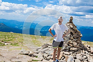 Man hiker relaxing on top of hill and admiring beautiful mountain