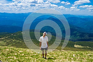 Man hiker relaxing on top of hill and admiring beautiful mountain