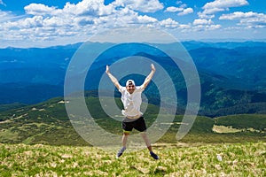 Man hiker relaxing on top of hill and admiring beautiful mountain