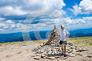 Man hiker relaxing on top of hill and admiring beautiful mountain