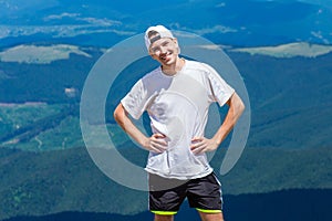 Man hiker relaxing on top of hill and admiring beautiful mountain