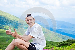 Man hiker relaxing on top of hill and admiring beautiful mountain valley view